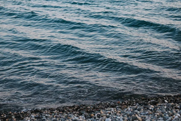 Mavi deniz, çakıl taşlı kıyıları yıkıyor..
