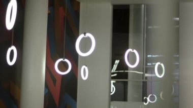 Beyaz duvarlı oda, yuvarlak lambalar ve duvarlarda resimler.