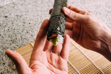 Maki suşisi yuvarlandıktan sonra elleri açıkta kalır. Ev yapımı Japon yemeği..