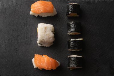 Maki, uramaki ve nigiri 'li suşi yemeği. Somon, ton balığı, avokado ve pirinç tahtada. Japon yemeği ev yapımı. Üst Görünüm
