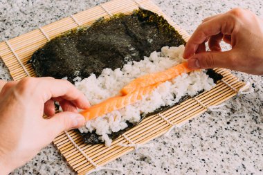 Granit bir masada somon, pirinç ve yosun ile maki suşi yapıyorum. Japon yemeği pişirmek. Üst Görünüm.