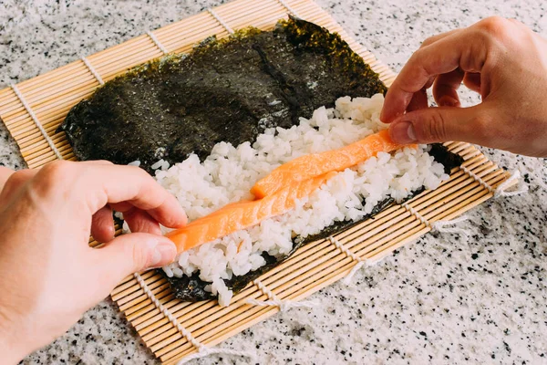 Granit bir masada somon, pirinç ve yosun ile maki suşi yapıyorum. Japon yemeği pişirmek. Üst Görünüm.
