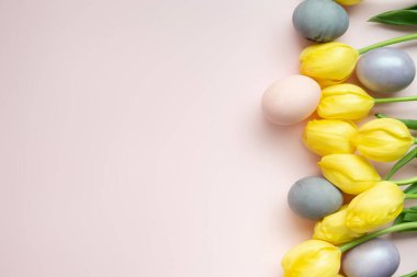 Boyalı Yumurtalar ve sarı laleler pembe arkaplan, düz yatış, Mutlu Paskalyalar konsepti için boşluk