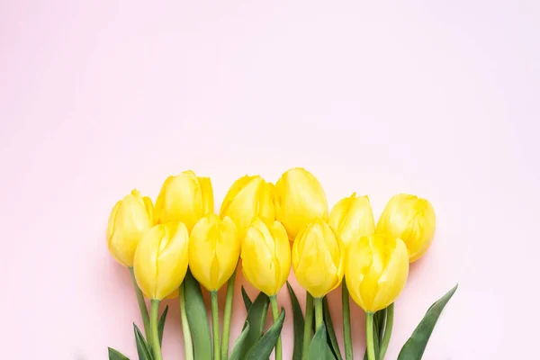 Painted Eggs, yellow tulips. silver serpentine and confetti with space for text on grey background, flat lay, Happy Easter, woman or mother day concept