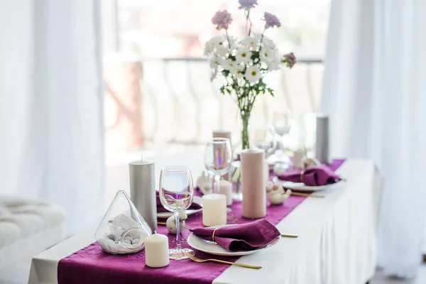 Marsala menekşe tekstil peçetesi ve masa örtüsü, paskalya yumurtası, beyaz tabak ve altın çatal bıçak takımı, mum ve şarap için bardak. mor renk