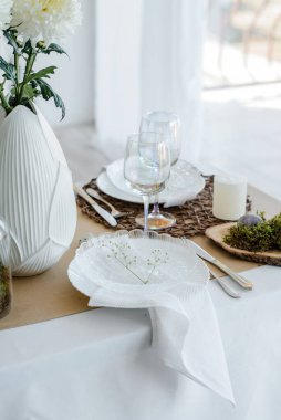 Paskalya bayramı zarif ev dekorasyonu geleneksel bayram yemeği için dekore edilmiş masa bahar çiçekleri, Paskalya dekoru, beyaz peçeteler ve yumurtalarla süslenmiş.