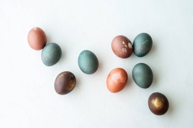 Beyaz taş arka planda boyanmış yumurtalar. Mutlu Paskalyalar. Doğal renkli yumurta, pastel ve doğal renk..