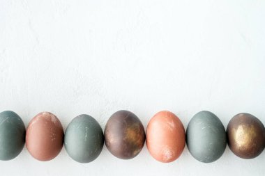 Beyaz taşlı arka planda boyanmış yumurtalar, kopyalama alanı. Mutlu Paskalyalar. Doğal renkli yumurta, pastel ve doğal renk. Boşluğu kopyala.