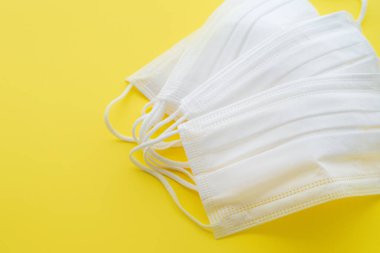 Grip ve diğer hastalıklara karşı korunmak için sarı arka planda beyaz maske. Cerrahi koruyucu maske. Beyaz arka planda tıbbi solunum bandajı var. Virüsün ve salgının yayılmasını önlemek. Coronavirus koruması