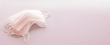 Pembe arka planda beyaz renkli tıbbi maskeler var. Kirliliğe, virüse, gribe ve koronavirüse karşı yüz maskesi koruması. Sağlık hizmeti konsepti. Boşluğu kopyala, metin için pankart.