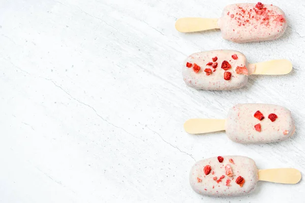 Collection of chocolate ice cream on stick with red sprinkles on white background. Copy space.