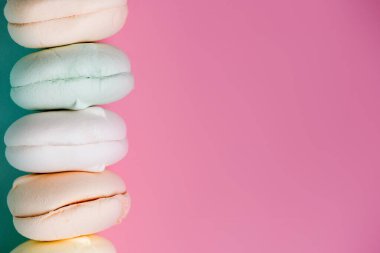 Renkli tatlı zephyr şekerlemeleri pembe arka planda. Pastel gölgelerde hava şekerlemesi. Kapat.