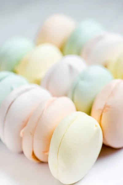 Air marshmallows in pastel shades on a white background. Gentle pastel colored zephyr in light key