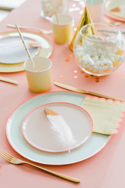 Çocuklar için dekoratif şenlik masası. Parti yemeği. Tekstil pembesi masa örtüsü, kağıt renkli tabaklar. Doğum günün kutlu olsun kız ya da bebek partisi dekorasyonu