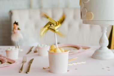 Altın fırıldak kağıt bardakta, kız doğum günü için dekoratif parti masasında.