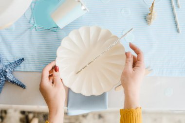 Dekoratörün elleri. Doğum günü ya da bebek partisi için masalara mavi beyaz renkte servis yapan bir kadın. Kapat, üst görünüm