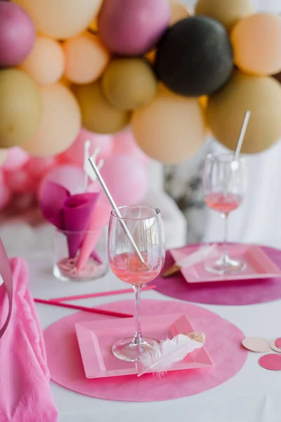 Pembe renkli şenlik masası, beyaz tabaklar, kokteyl çubuklu bardaklar. Renkli balonlar. Doğum günü, bebek partisi ya da kızlar partisi.