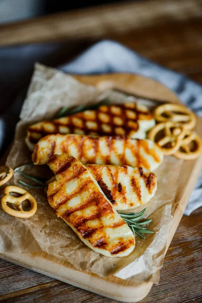 Tahta bir tahtanın üzerinde biberiyeli kızarmış halloumi peyniri ve küçük krakerler.