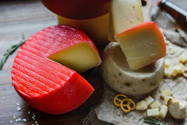 Red cheese wheel and assorted cheeses on wooden table