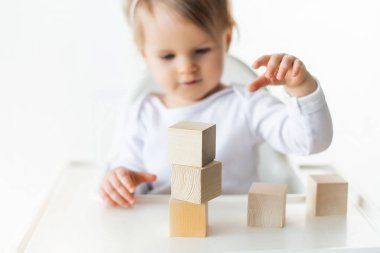 Tahta küplerle oynayan tatlı bir bebek. Küçük çocuk inşa kulesi. Çocuklar için inşaat bloğu. Montessori eğitim yöntemi. Seçici odak