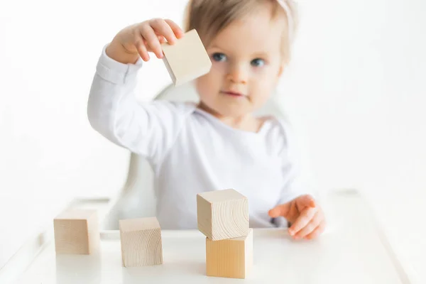 Tahta küplerle oynayan tatlı bir bebek. Küçük çocuk inşa kulesi. Çocuklar için inşaat bloğu. Montessori eğitim yöntemi. Seçici odak