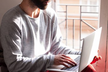 Gözlüklü genç adam, sabah erkenden bütün işlerini halletmek için dizüstü bilgisayarı üzerinde çalışıyor.