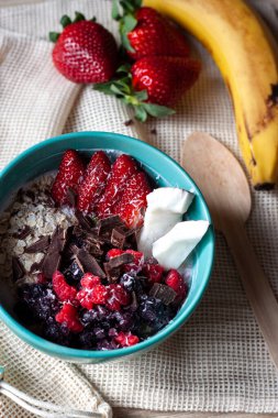 Sağlıklı meyve suyu kasesi granola, taze çilek, yabanmersini, hindistan cevizi, muz, çikolata, yoğurt ve chia çekirdeği. Sağlıklı yemek, atıştırmalık ya da kahvaltı.