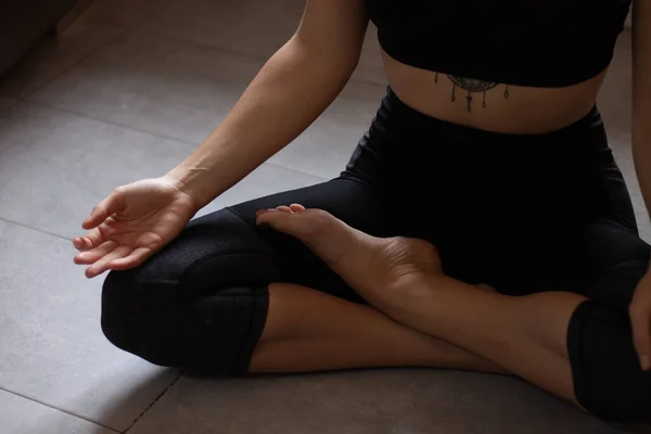 Evde uyandıktan sonra sabah yogası yapan güzel bir kadının yakın çekimi. Dişi model bacak bacak üstüne atarak oturuyor. Kolay poz, Sukhasana duruşu ve meditasyon..