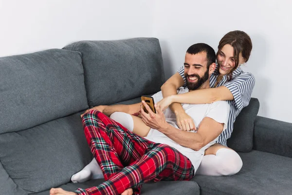 Relaxado Jovem Mulher Com Homem Usando Smartphone Sofá Casa — Fotografia de Stock