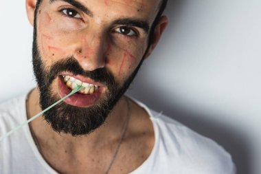 Yüzünde ruj izi olan yakışıklı genç bir adam sakızla oynuyor.