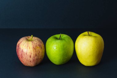 Siyah arkaplanda 3 farklı taze elma rengi