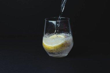 Şeffaf bardağa limonlu cin toniği dolduruyorum.