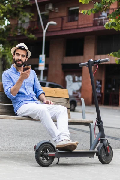 Hombre Barbudo Con Scooter Eléctrico Banco Mientras Habla Teléfono Inteligente — Foto de Stock