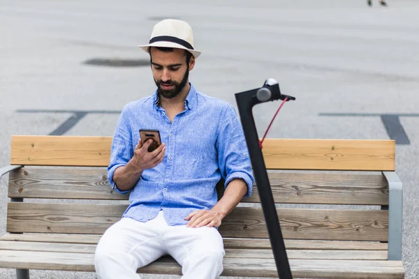 Junger Mann Mit Elektroroller Auf Einer Bank Auf Der Suche — Stockfoto