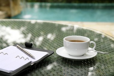 Bir fincan kahve, organizatör ve kalem masaya.