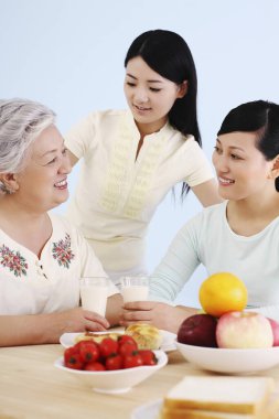 Kıdemli kadın ve kadınlar birlikte kahvaltı yapıyorlar.