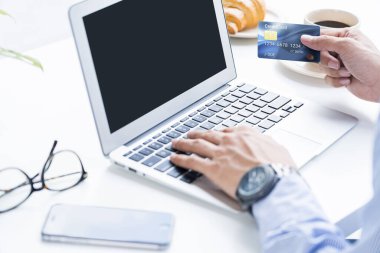 Çevrimiçi alışveriş için kredi kartı tutan adam.