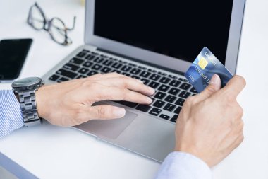 Çevrimiçi alışveriş için kredi kartı tutan adam.