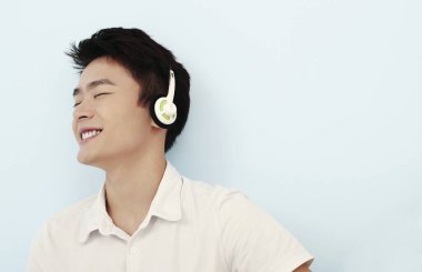 Kulaklıkla müzik dinleyen adam, gözleri kapalı.