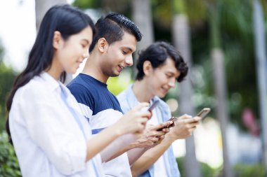 Akıllı telefonlarını kullanan üç genç yetişkin.