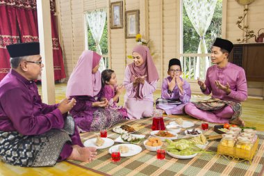 Muslim family saying prayers before meal clipart