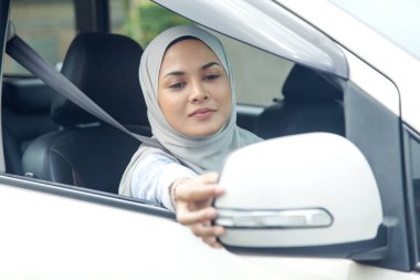 Kadın dikiz aynasını ayarlıyor.