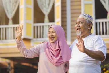 Gülümseyen yaşlı çift el sallıyor