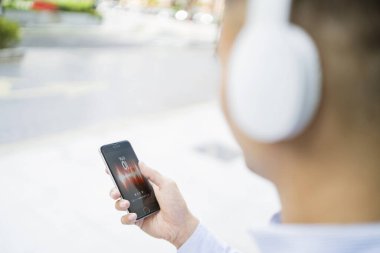 Telefonundaki şarkı listesinden şarkı seçen bir adam