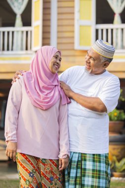 Ahşap evin önünde neşeli yaşlı çift