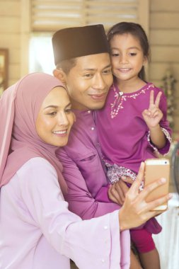 Malay ailesi akıllı telefonuyla fotoğraf çekiyor.