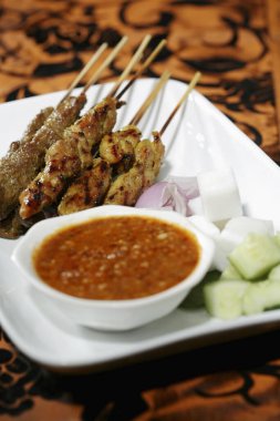 Fıstık soslu satay, soğan ve salatalık dilimleri.