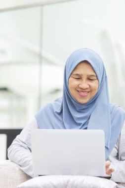 Dizüstü bilgisayar kullanırken gülümseyen son sınıf kadını.