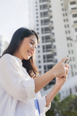 Akıllı telefon kullanan genç bir kadın.