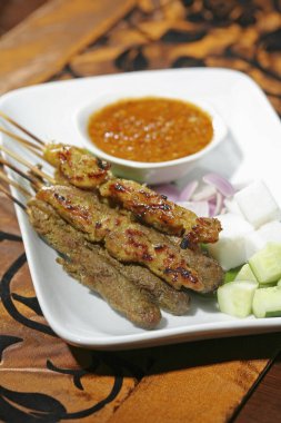 Fıstık soslu satay, soğan ve salatalık dilimleri.